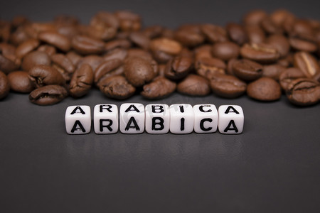 靠近用白色小方块写的 ARABICA 字样的新鲜烘焙咖啡豆的特写。