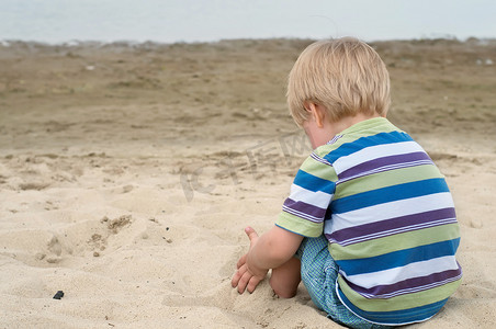 坐在沙滩上的蹒跚学步的小男孩