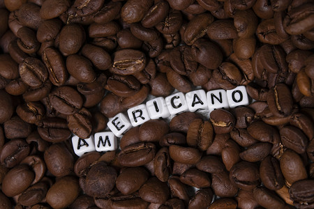 靠近用白色小方块写的 AMERICANO 字样的新鲜烘焙咖啡豆的特写。