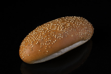 芝麻面包摄影照片_深色背景下的热狗芝麻面包。面包