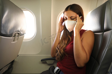 COVID-19 戴 KN95 FFP2 面具的年轻女性在飞机上感觉不适。