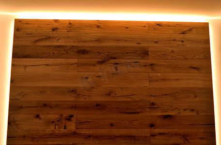 墙壁的特写镜头，上面铺有天然纹理的镶木地板，由 LED 灯带分隔。