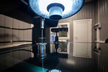 坐标摄影照片_CMM - 坐标测量机 - 接触式探针测量玻璃台面上的圆形铝制零件。