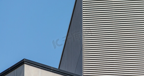 灰色线条线条摄影照片_灰色高楼的条纹墙与晴朗的蓝天相映成趣