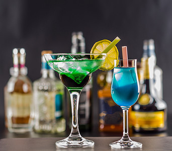 蓝色饮料摄影照片_原形瓶背景的彩色饮料，加冰块的鸡尾酒