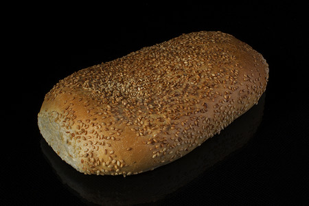 黑色背景上用芝麻切片的面包 面包