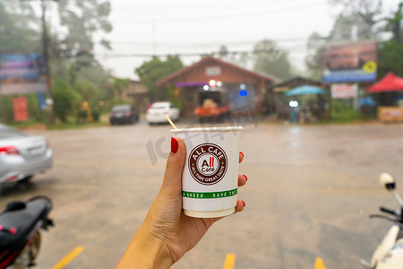 下雨热摄影照片_在等待热带雨结束的同时，在当地泰国杂货店的树冠下享用热咖啡