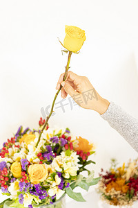 女人的手把黄玫瑰放在花束上
