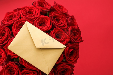 艺术传达摄影照片_情人节的情书和送花服务、豪华的红玫瑰花束和红色背景的卡片信封