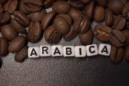 能量方块摄影照片_靠近用白色小方块写的 ARABICA 字样的新鲜烘焙咖啡豆的特写。
