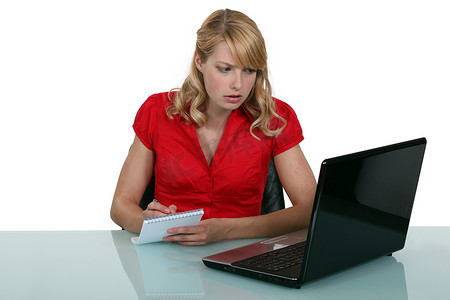职业女人摄影照片_沉思的金发女人从笔记本电脑屏幕上做笔记