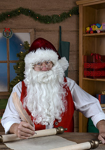淘气摄影照片_圣诞老人在他的工作室里写下他的淘气和好人名单。