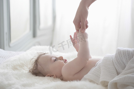 卧室毛毯摄影照片_可爱的男婴在卧室里牵着妈妈的手