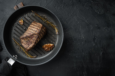 烤牛肉切块，在煎铁锅上，黑色背景，顶视图平躺，有文本复制空间