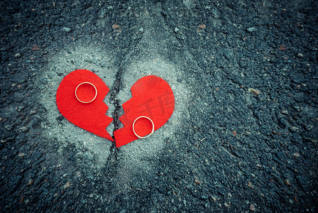离婚概念-破碎的心与破裂的沥青上的结婚戒指。