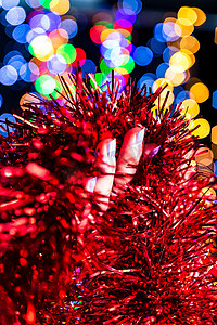 圣诞花环摄影照片_拿着圣诞花环装饰孤立在背景与模糊的灯光。