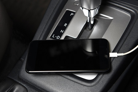 自动充电摄影照片_智能手机在汽车中控台上充电的特写。