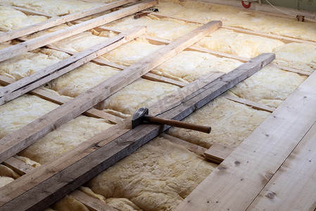 用木匠锤在玻璃棉上铺木板地板保温保暖，用于家庭地板修复