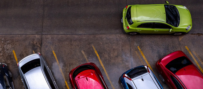 停在混凝土停车场的汽车的顶视图，街道上有黄线交通标志。