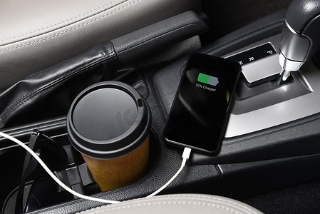 智能手机插入现代汽车控制台的充电端口，特写为咖啡杯和太阳镜。