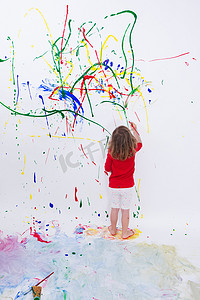 年轻的小孩在白色的大墙上画画
