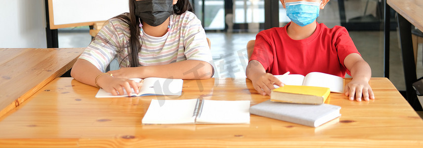 儿童口罩摄影照片_女孩男孩学生戴着口罩学习写笔记做作业。