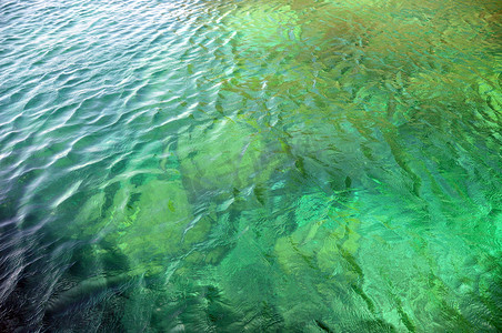 波纹清澈的蔚蓝水背景，浅绿色美丽透明水的背景，在阳光下反射的波纹。