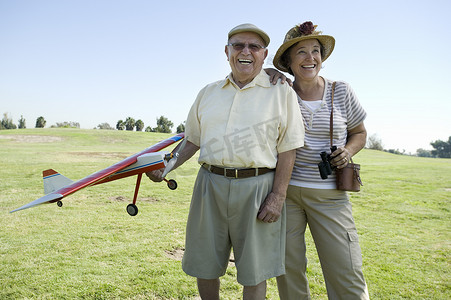 外勤摄影照片_站在拿着模型飞机的外勤人员上的老年夫妇
