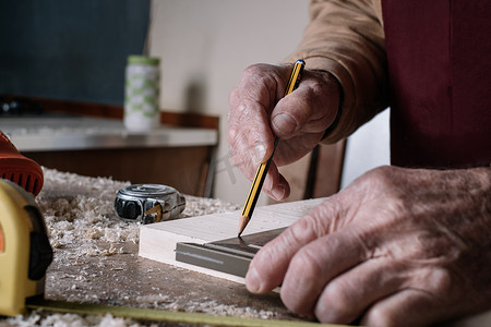 木匠用铅笔和金属方块在桌子上进行测量