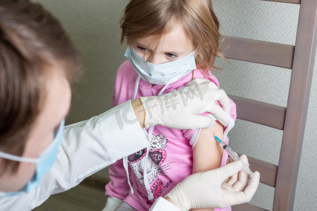 戴医用面具的白人小女孩坐着接受疫苗
