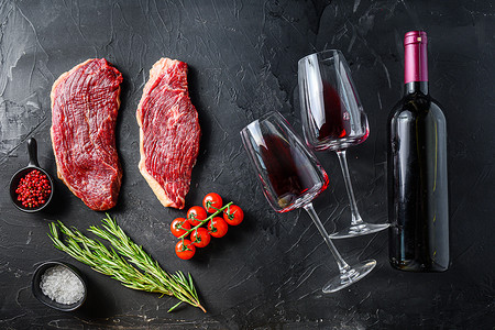 黑色质感摄影照片_有机 picanha 牛排靠近瓶子和一杯红酒，在黑色质感的桌面视图上