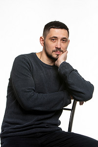一个穿着深色素色毛衣的普通人坐在高背椅上的肖像