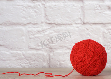 白砖墙背景上带毛线的红球