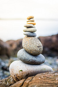 平衡、放松和健康：外面的石冢，模糊背景中的海洋