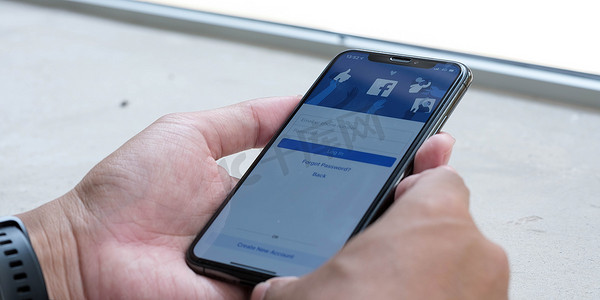 苹果x摄影照片_泰国清迈，2021 年 5 月 18 日：一位女士手持 iPhone X，屏幕上显示社交互联网服务 Facebook。
