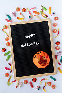 万圣节假期糖果，黑色字母板，白色背景上写着 Happy Halloween flat