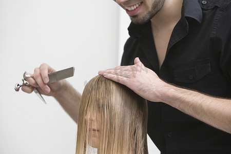 男人在理发店剪头发和梳理年轻女人的头发