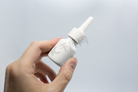 年轻人生病用鼻腔喷雾剂治疗鼻塞、喷鼻药水、手持鼻腔喷雾剂、特写药丸包在病人手中