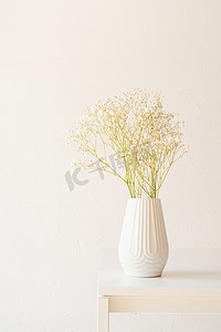 桌上白色花瓶中的白色满天星花，简约风格