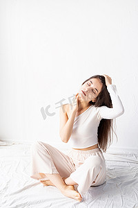 美丽的年轻女子的画像，穿着白色舒适的衣服，闭着眼睛坐在地板上