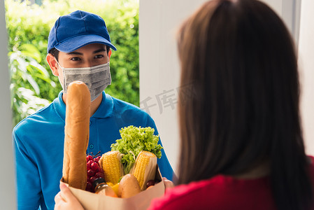 送货员戴防护面罩做杂货店，给女顾客送新鲜食物