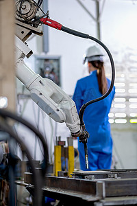 工厂机器人机器正在工作区的背景下与女工监控和检查电气系统一起工作。