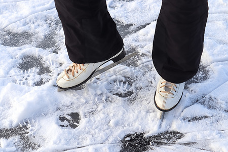 冻脚摄影照片_紧靠穿着滑冰靴站在冰上的女人脚。