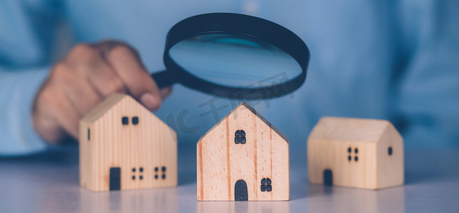 商人的手拿着放大镜看房子，用于检查和分析质量、检查和选择房屋、购买和搜索住宅和投资、商业和房地产概念。