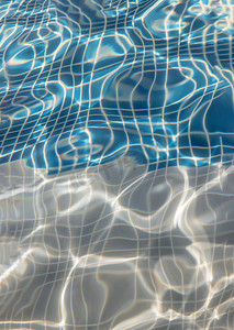 装饰水波纹摄影照片_太阳反射在游泳池蓝色清楚的水波纹与马赛克底部从上面。