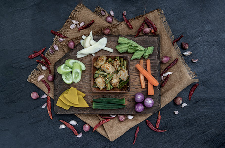 泰国菜，炒鱼丸配红咖喱酱和长豆配料和新鲜蔬菜在木背景上。