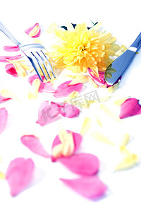 用大丽花和玫瑰花瓣隔开的银叉和刀