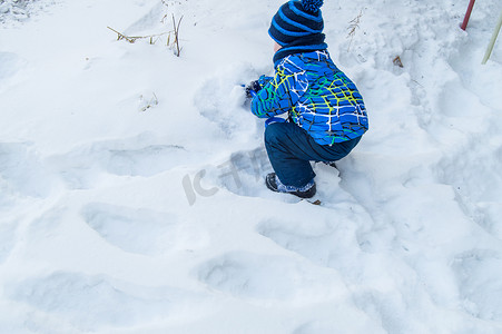 迷人的小男孩在冬日挖雪蓝色小铲子