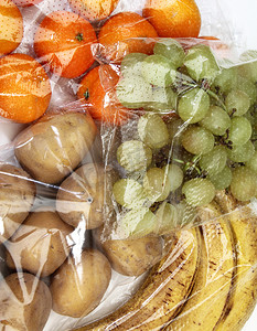 玻璃纸袋中的橘子、葡萄、香蕉和土豆