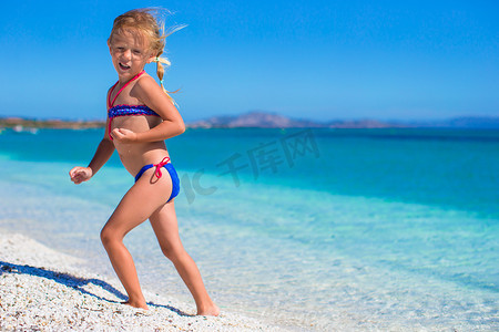在白色沙滩和碧绿海水的热带海滩上享受假期的小女孩